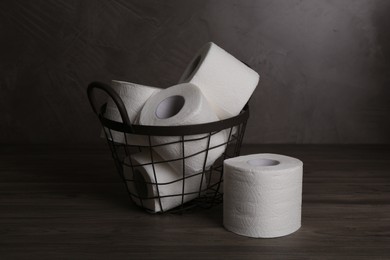 Soft toilet paper rolls in metal basket on wooden table