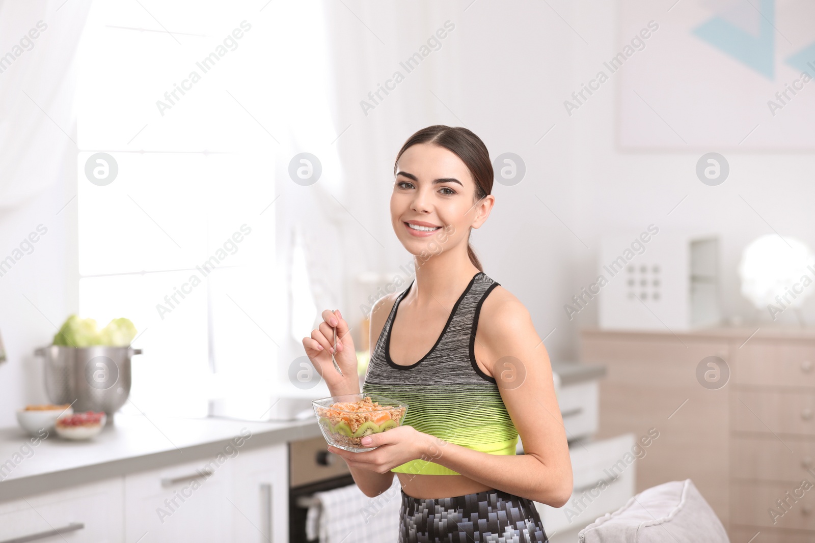 Photo of Young woman in fitness clothes having healthy breakfast at home