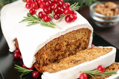 Photo of Traditional classic Christmas cake decorated with cranberries and rosemary on black plate, closeup