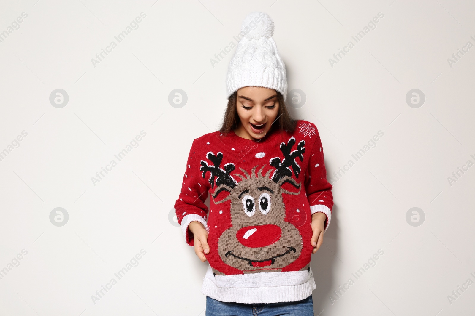 Photo of Young woman in Christmas sweater and knitted hat on white background