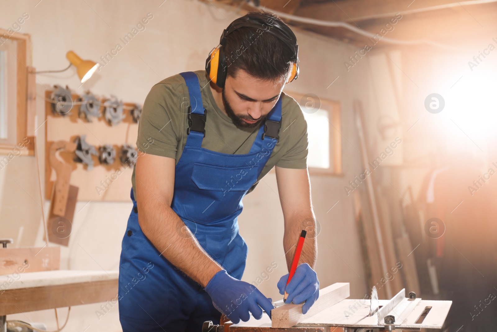 Photo of Professional carpenter making mark on wooden bar in workshop