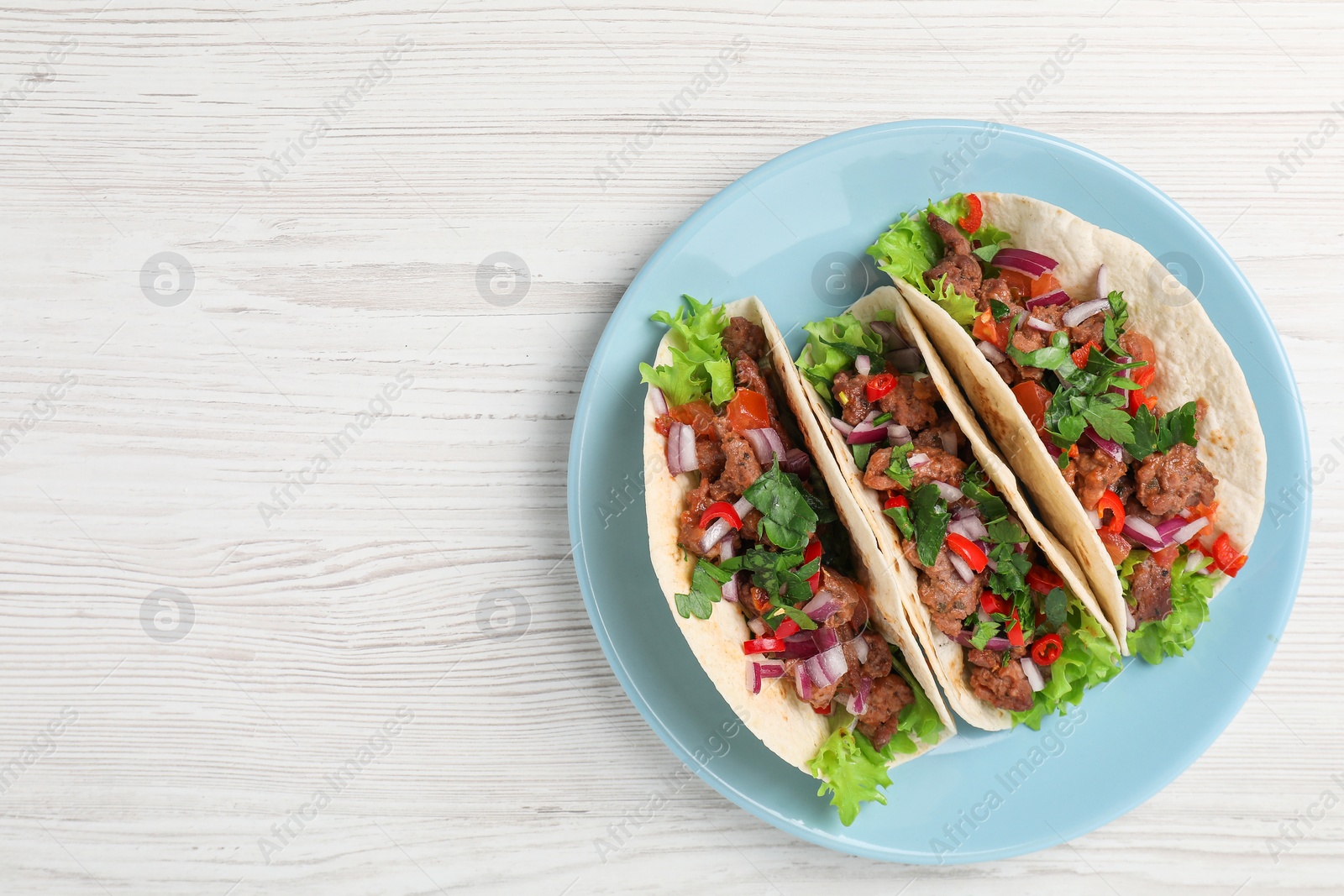 Photo of Delicious tacos with meat and vegetables on wooden table, top view. Space for text