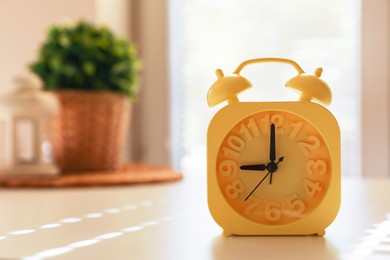 Yellow alarm clock on table indoors. Space for text