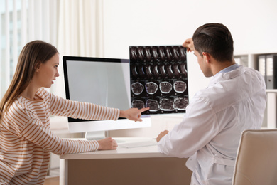 Photo of Orthopedist showing X-ray picture to patient at table in clinic