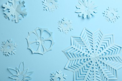 Photo of Many paper snowflakes on light blue background, flat lay