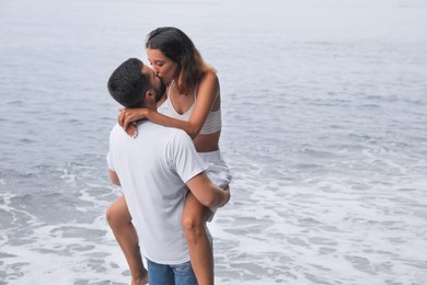 Photo of Young couple kissing near sea. Space for text