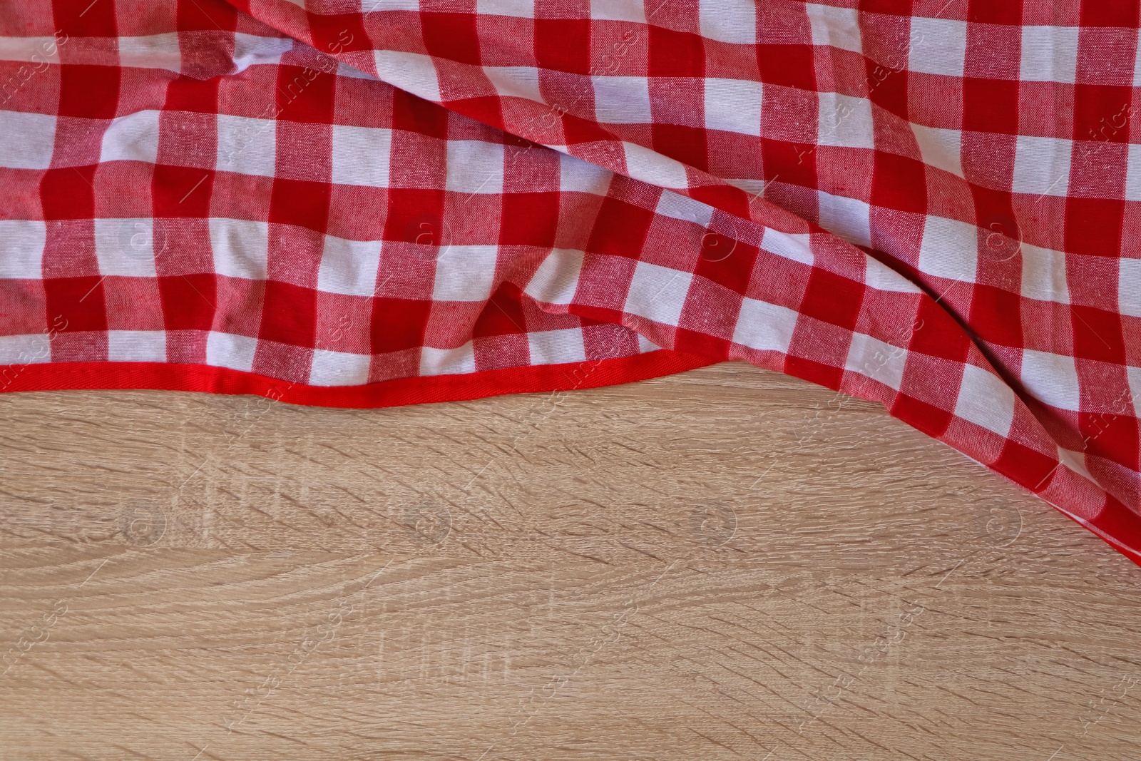 Photo of Checkered picnic cloth on wooden table, top view. Space for text