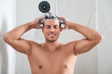 Photo of Handsome man washing hair in shower at home