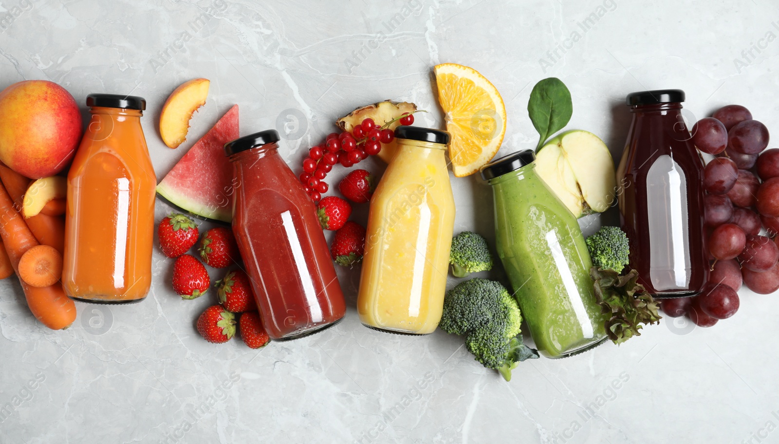 Photo of Bottles of delicious juices and fresh fruits on marble table, flat lay