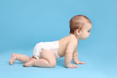 Photo of Cute little baby in diaper crawling on light blue background