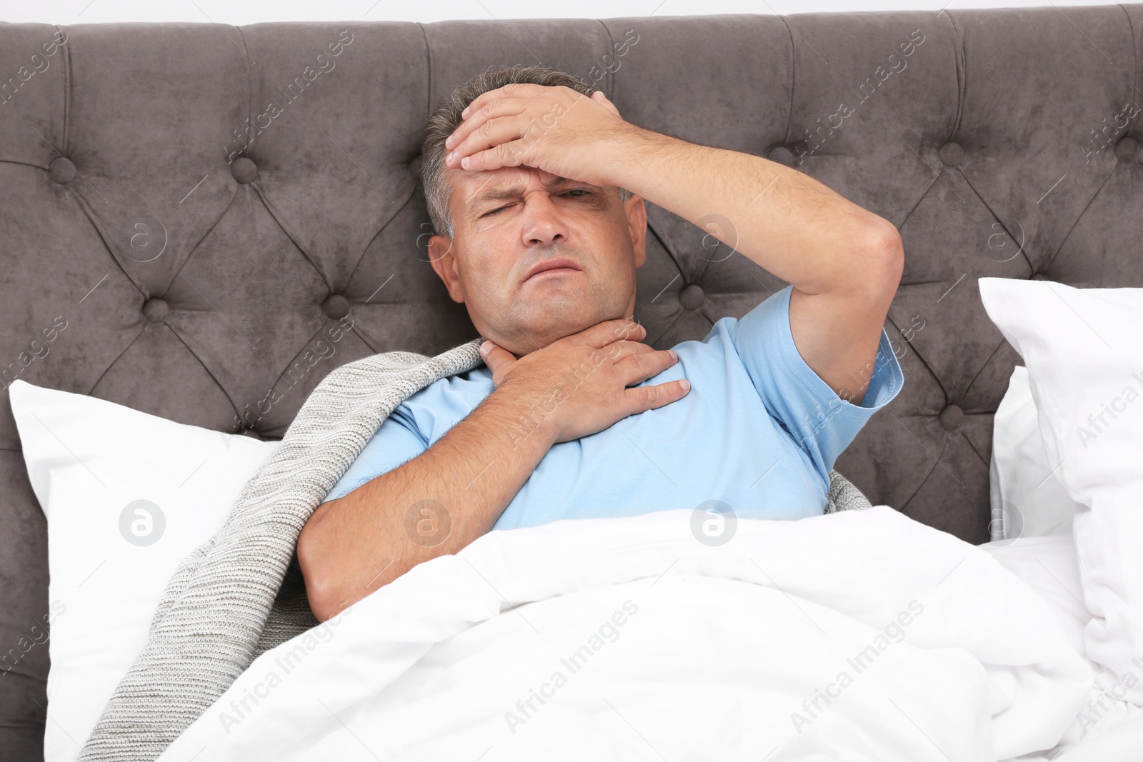 Photo of Man suffering from cough and headache in bed at home