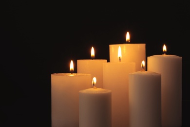 Photo of Burning candles on dark background, space for text. Symbol of sorrow