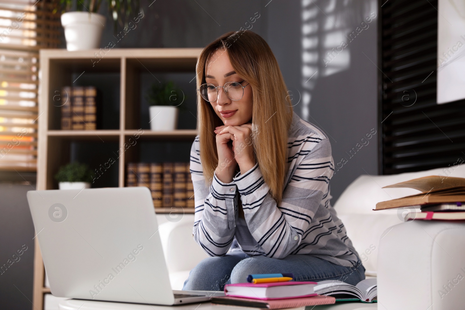 Photo of Young woman watching webinar on sofa at home