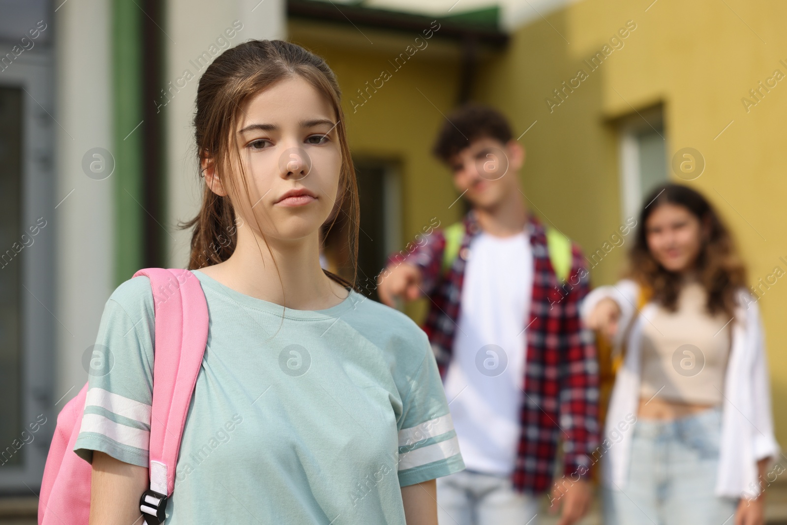 Photo of Teen problems. Students pointing at upset girl outdoors, selective focus