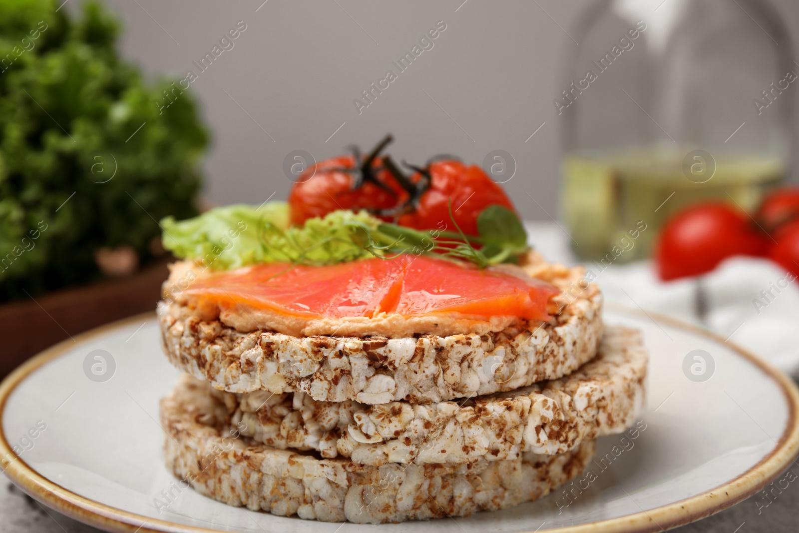 Photo of Crunchy buckwheat cakes with salmon, tomatoes and greens on plate, closeup