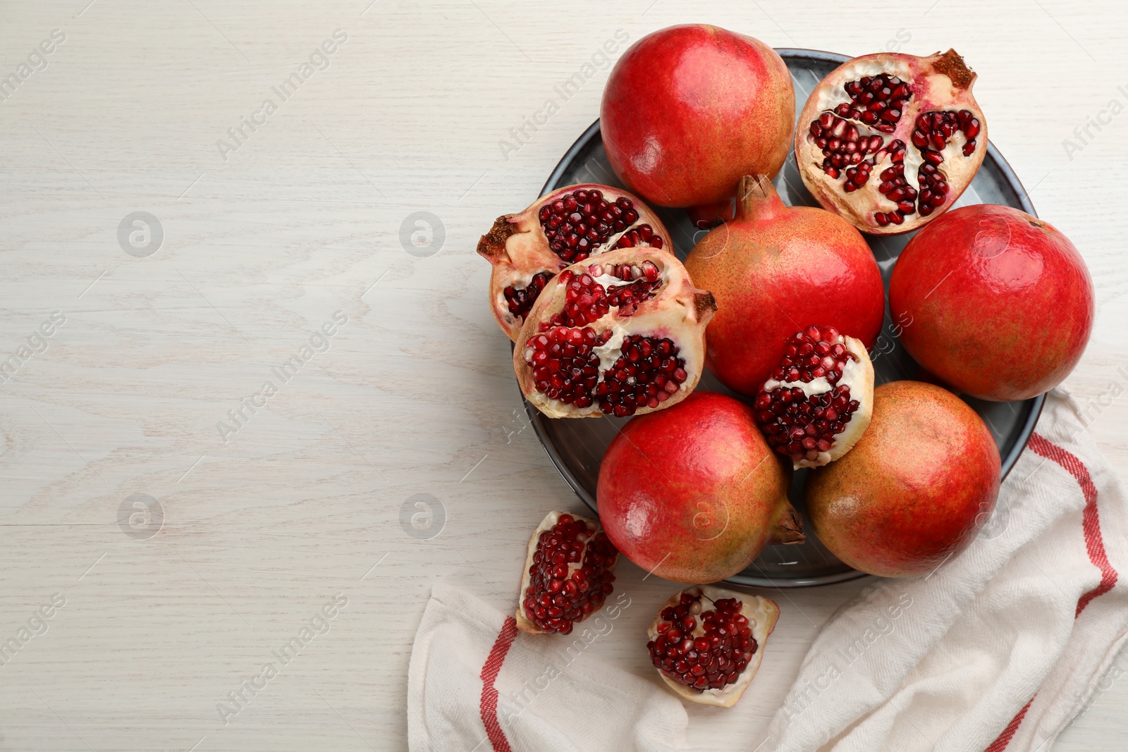 Photo of Delicious ripe pomegranates on white wooden table, flat lay. Space for text