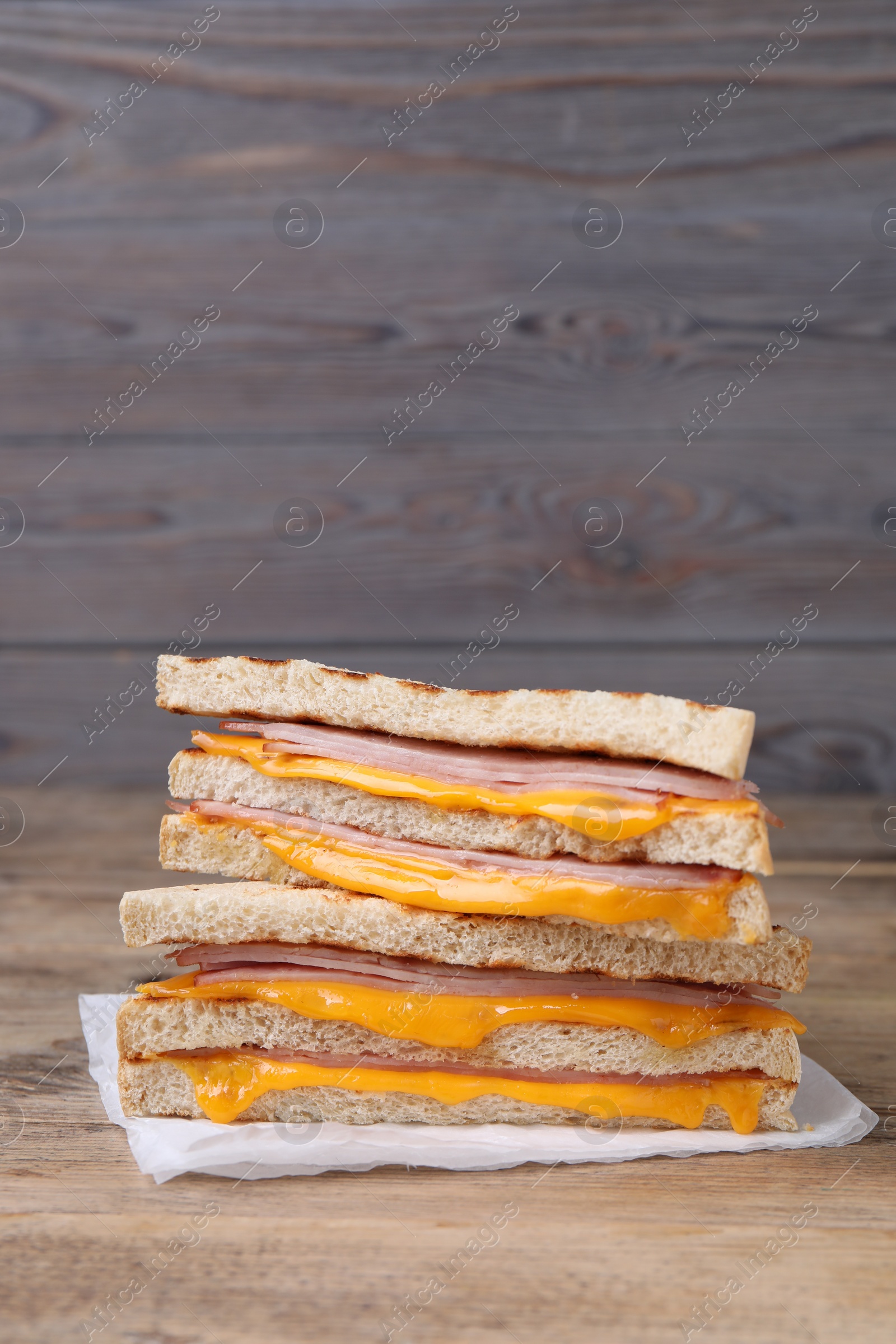 Delicious grilled sandwiches with ham and cheese on wooden table. Space for text Photo of Delicious grilled sandwiches with ham and cheese on wooden table. Space for text