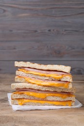 Photo of Delicious grilled sandwiches with ham and cheese on wooden table. Space for text