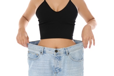 Photo of Slim woman in oversized jeans on white background, closeup. Weight loss