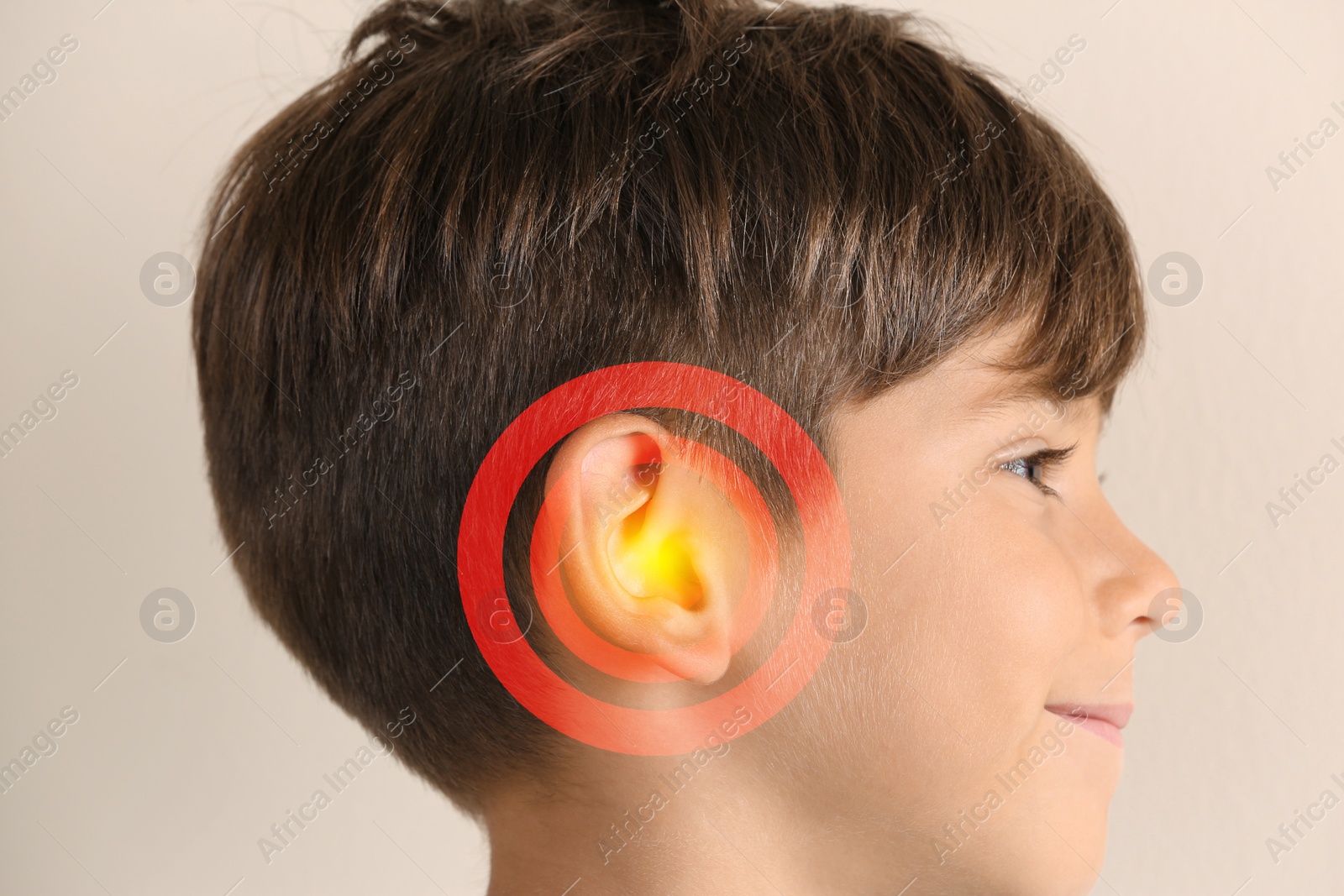 Image of Little boy on beige background, closeup. Hearing problem