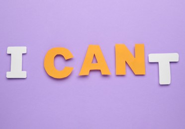 Photo of Motivation concept. Changing phrase from I Can't into I Can by removing paper letter T on violet background, top view