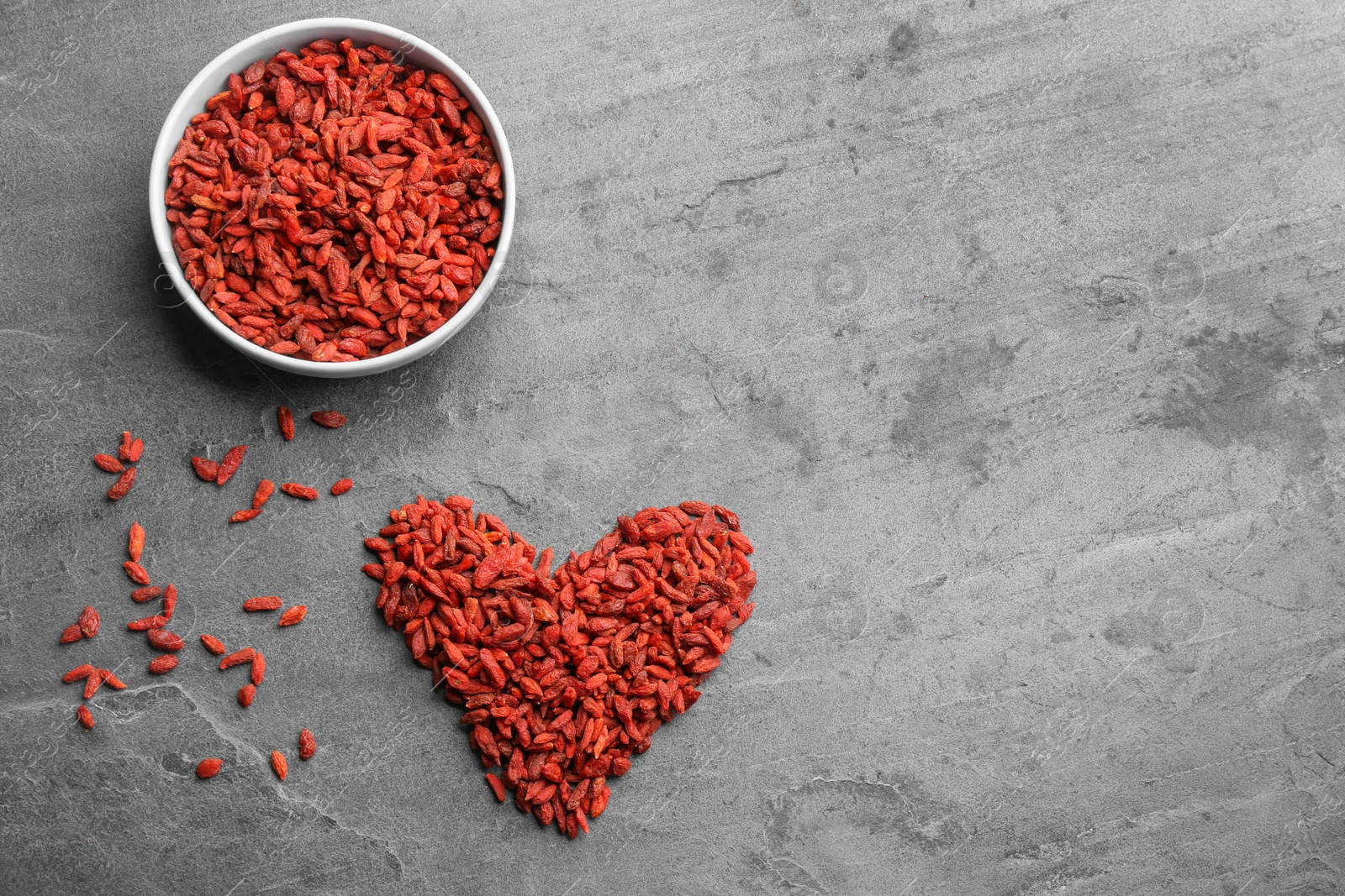 Photo of Flat lay composition with dried goji berries on grey table, space for text. Healthy superfood