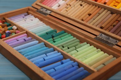 Photo of Drawing pastel set in wooden box light blue table, closeup