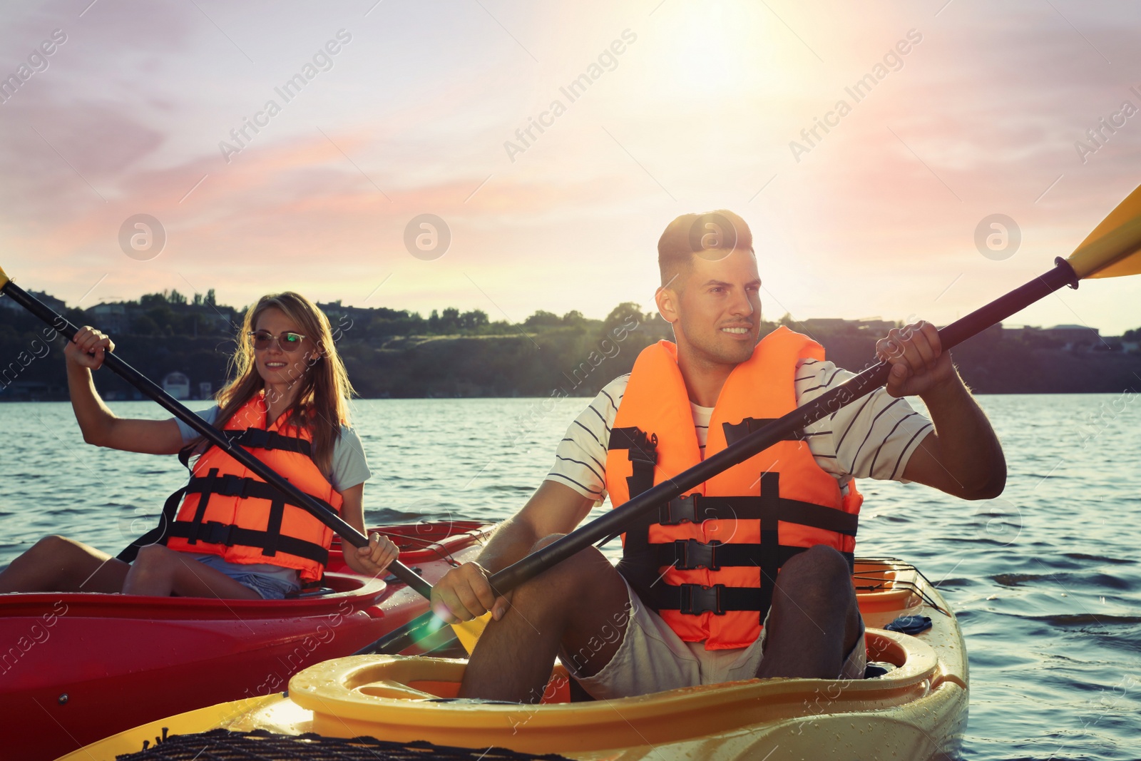 Photo of Couple in life jackets kayaking on river. Summer activity