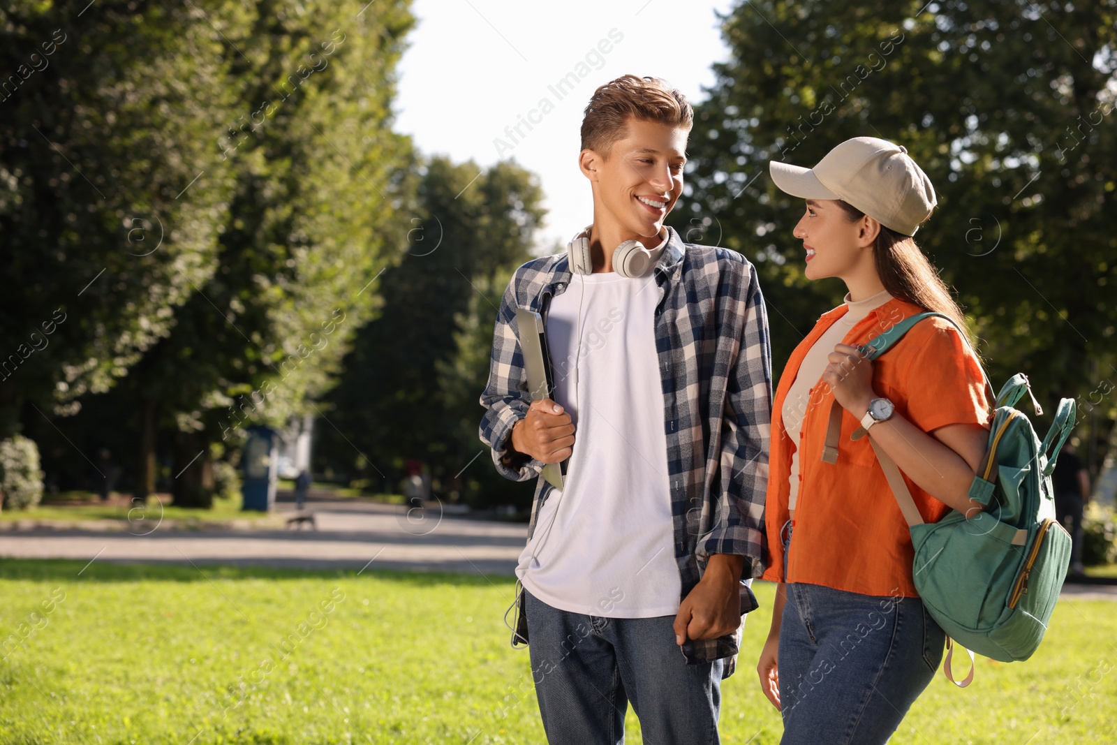 Photo of Happy young students spending time together in park