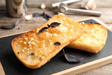 Photo of Board with delicious homemade garlic bread on table