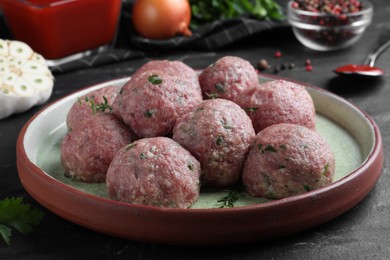 Photo of Many fresh raw meatballs on black table