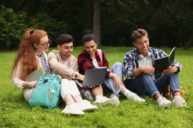 Photo of Group of happy young students learning together on green grass in park