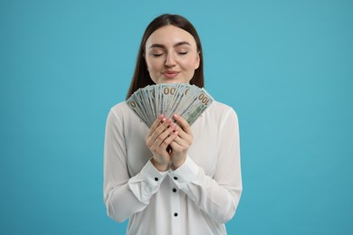 Photo of Smiling woman with dollar banknotes on light blue background