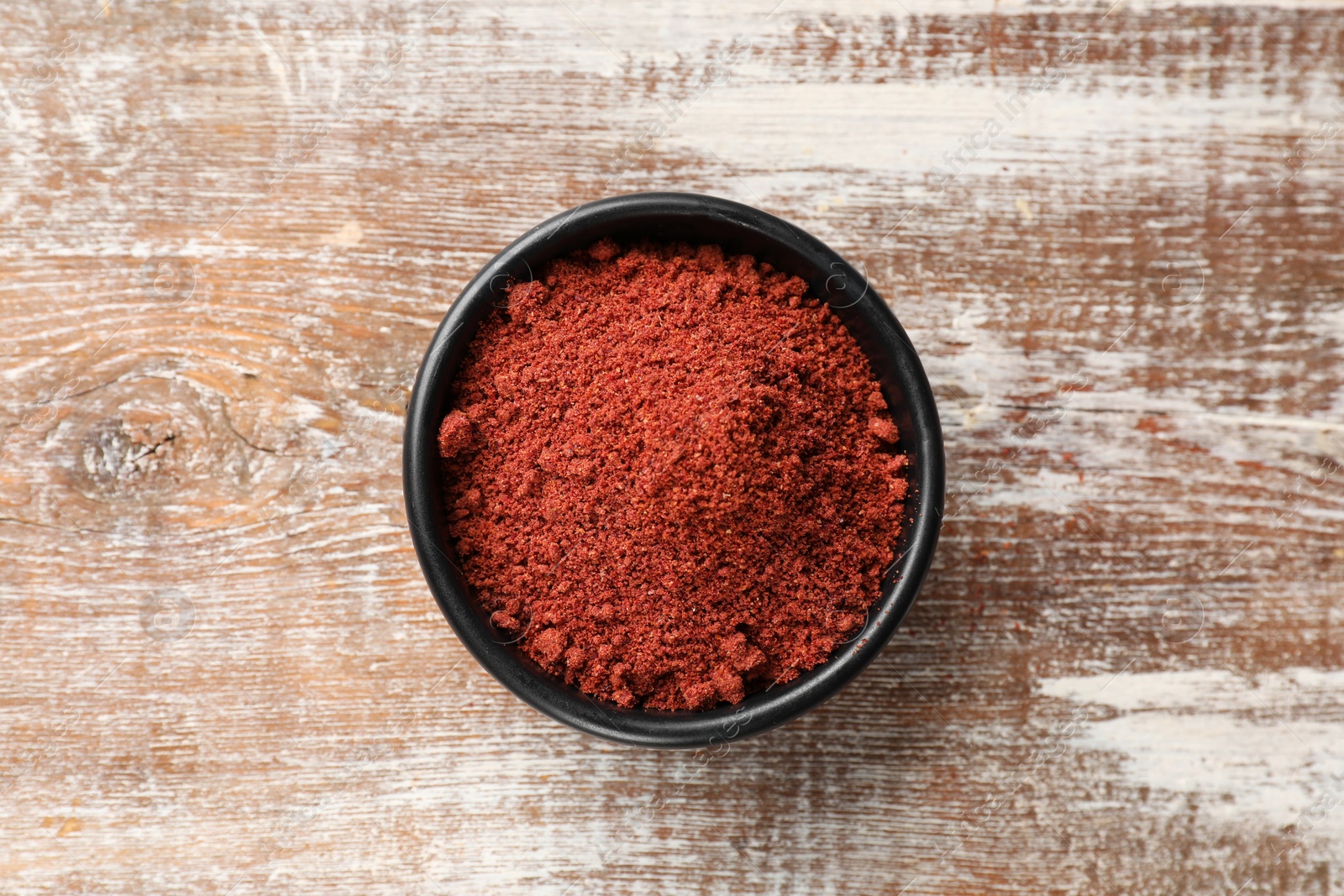 Photo of Cranberry powder in bowl on wooden table, top view