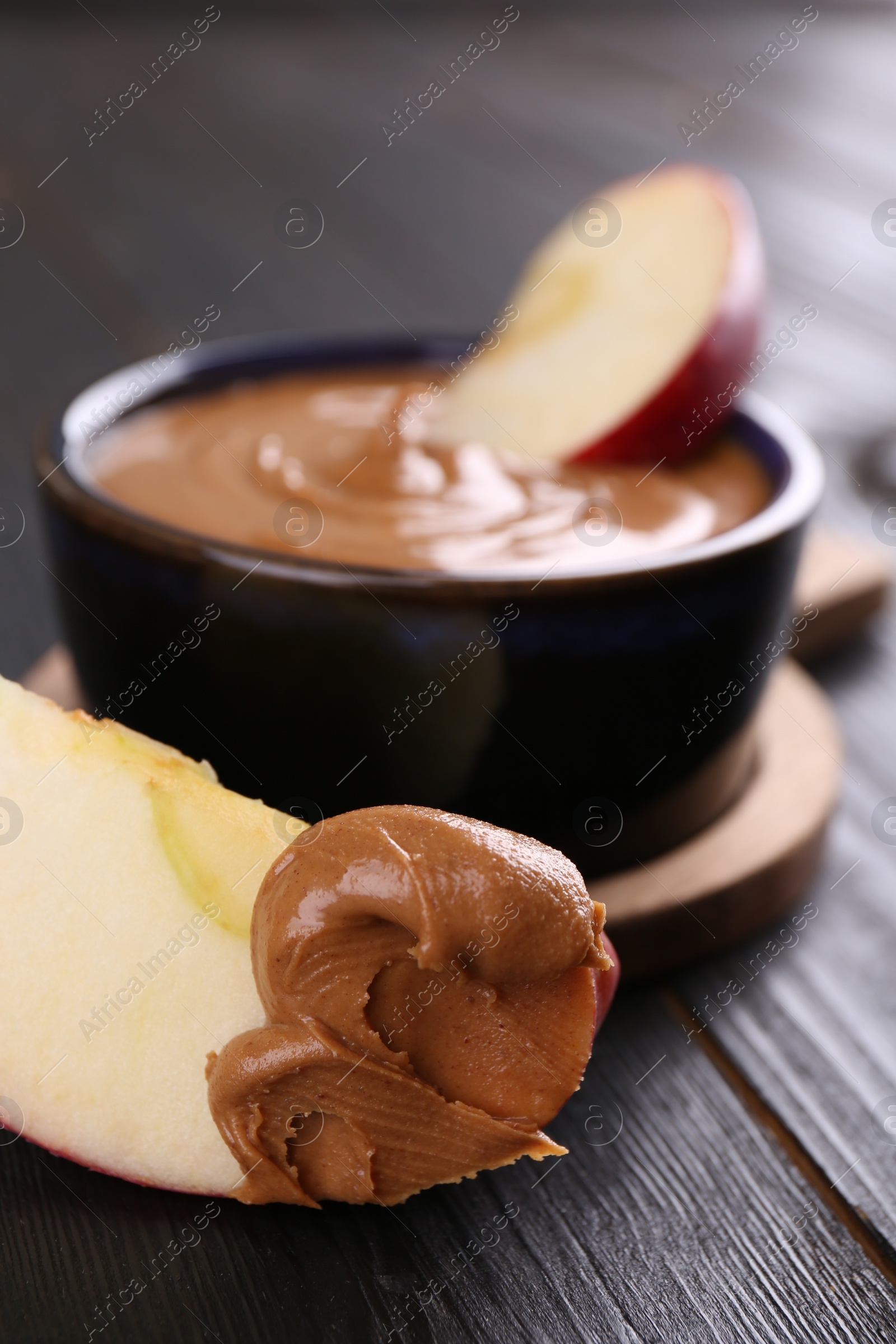 Photo of Slices of fresh apple with peanut butter on wooden table, closeup