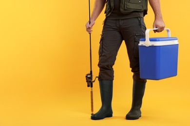 Photo of Fisherman with fishing rod and cool box on yellow background, closeup. Space. for text