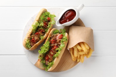 Photo of Tasty hot dogs with chili, lettuce, ketchup and French fries on white wooden table, top view