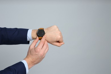 Photo of Closeup view of businessman wearing wristwatch against grey background, space for text. Time management