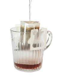 Photo of Pouring hot water into glass cup with drip coffee bag isolated on white