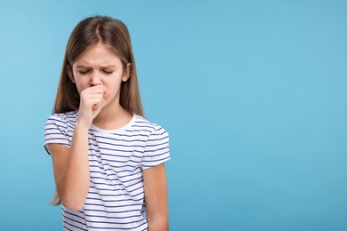 Sick girl coughing on light blue background, space for text