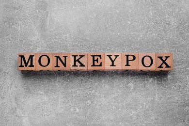 Photo of Word Monkeypox made of wooden cubes on light grey background, top view