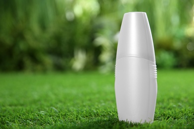 Photo of Bottle of insect repellent spray on green grass. Space for text