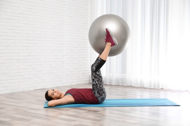 Young beautiful woman with ball doing exercise at home. Workout and fitness