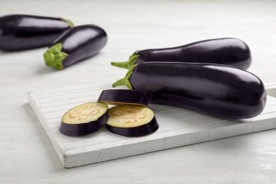 Photo of Wooden board with ripe eggplants on table