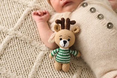 Top view of adorable little baby with deer toy lying on blanket, closeup. Space for text
