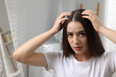 Photo of Emotional woman examining her hair and scalp at home. Dandruff problem