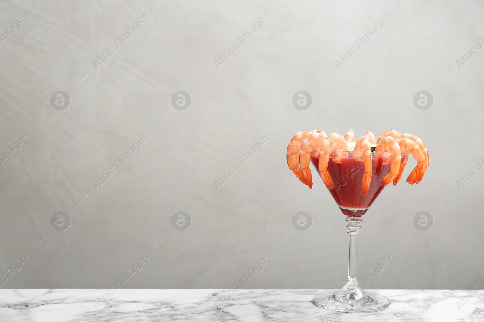 Photo of Shrimp cocktail with tomato sauce on marble table. Space for text