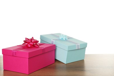 Photo of Pink and light blue gift boxes on wooden table against white background