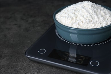 Electronic scales with flour on black table, closeup. Space for text