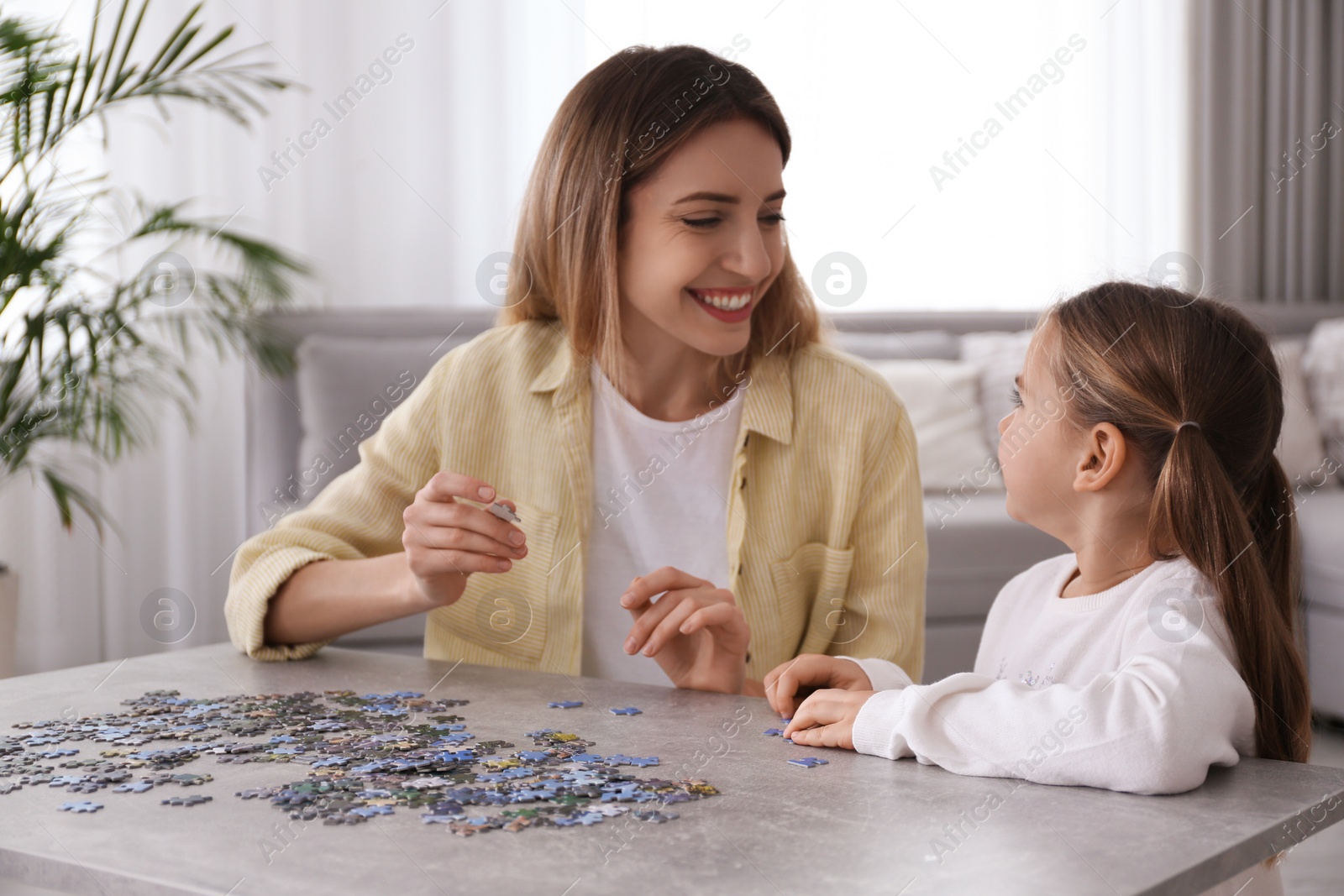 Photo of Woman and his little daughter playing with puzzles at home